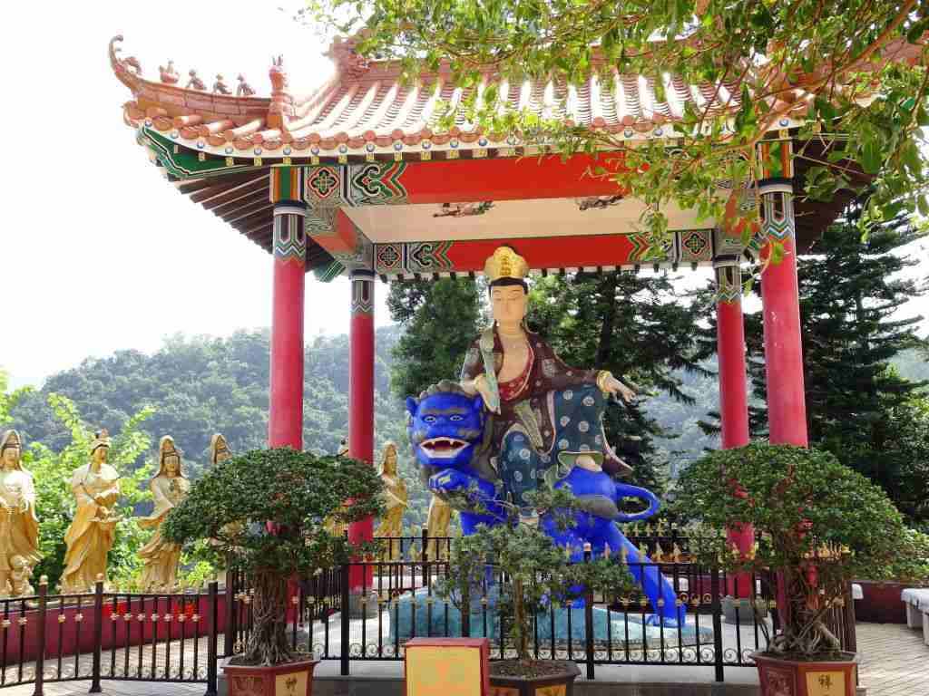 Buddha sitting on a blue dragon statue at the 10 Thousand Buddhas monastery