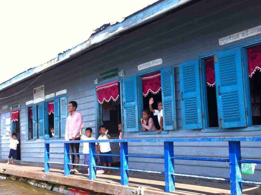 School children waving as the riverboat passes by on the way to Battambang in Cambodia