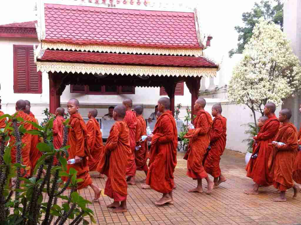 a group of barefoot Buddhist monks wearing rust coloured robes at the Royal Palce in Phnom Penh in Cambodia