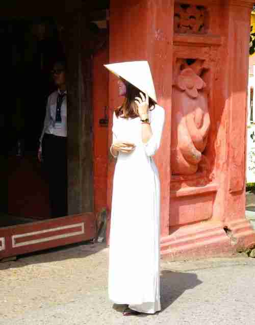 A Vietnamese girl wearing a long white dress and pointed hat