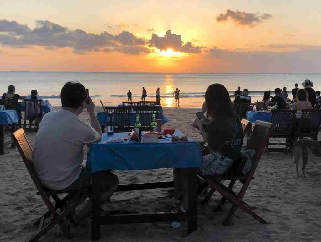 July in Bali eating dinner on Jimbaran beach and watching a beautiful sunset over the water