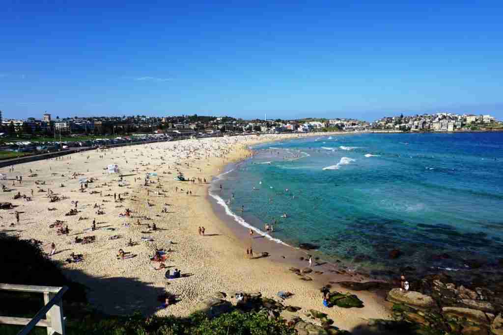 A crescent of golden sand and blue water at Bondi Beach on a sunny day