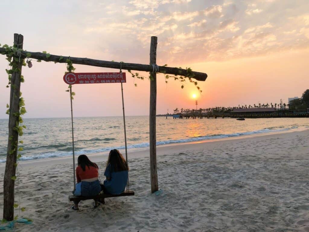 2 girls sitting on a swing watching the sunset on Occheuteal Beach in Sihanoukville