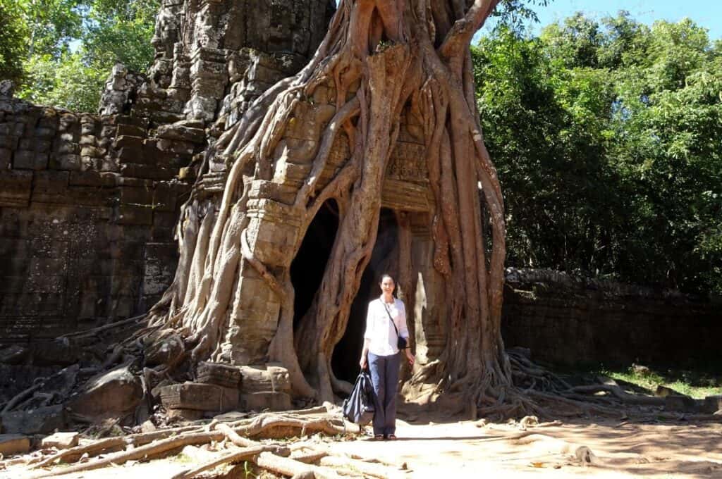 Standing near giant tree roots at Ta Prohm jungle temple Cambodia