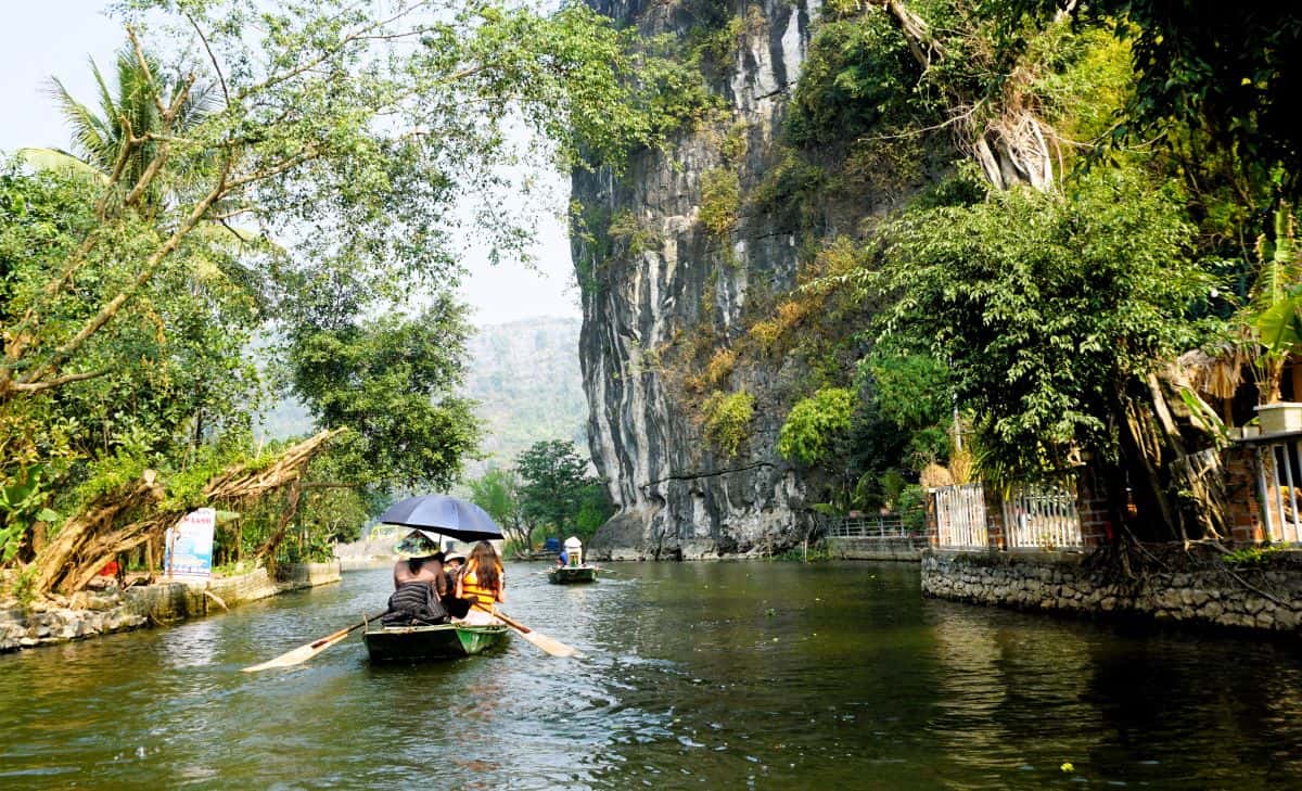 Row boat on a river beneath tall limestone cliffs on a northern vietnam itinerary