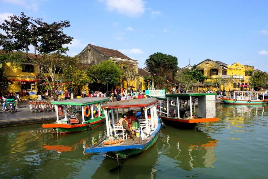colourful boats on the river in Hoi An Old Town with yellow historic buildings in the background
