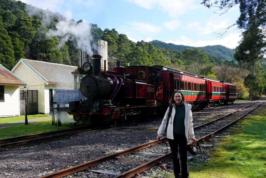 Linda standing near a heritage steam train at Lynchford station on the Heritage Wilderness Railway Queenstown Tasmania