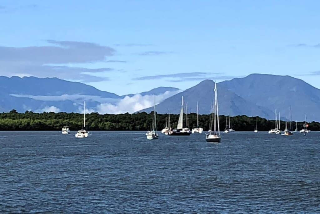 blue waters with sailing boats and mountains in the background