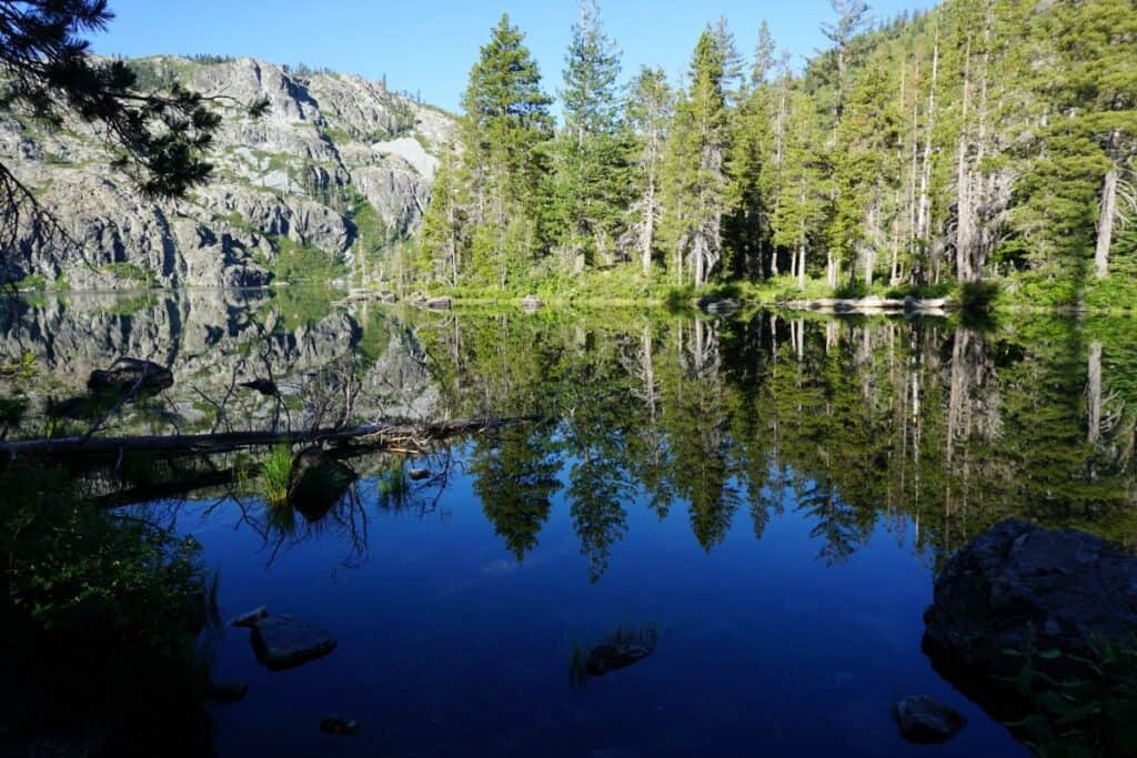 The still blue waters of Castle Lake reflecting the surrounding trees and mountains
