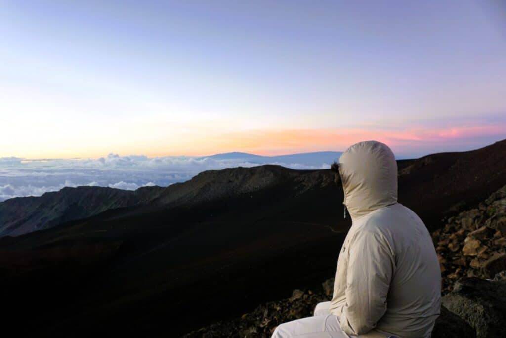 solo figure in a hoodie watching the sunrise on Haleakala Maui