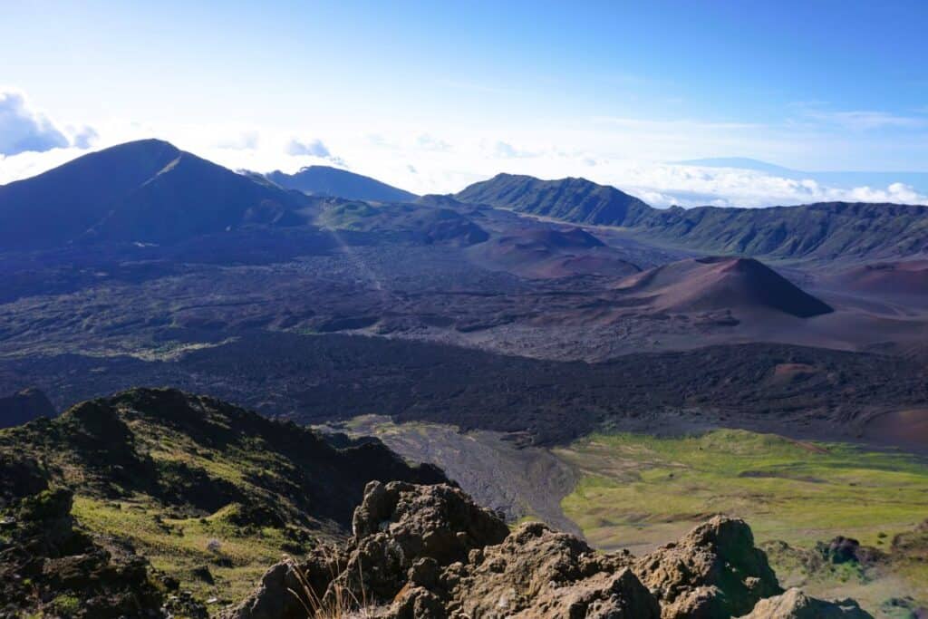 volcanic crater with dark lava flows, cones and green side